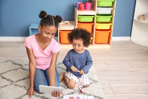 Linda chica afroamericana con tableta viendo dibujos animados en casa — Foto de Stock