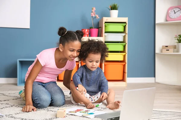 Lindas hermanas afroamericanas con portátil viendo dibujos animados en casa — Foto de Stock