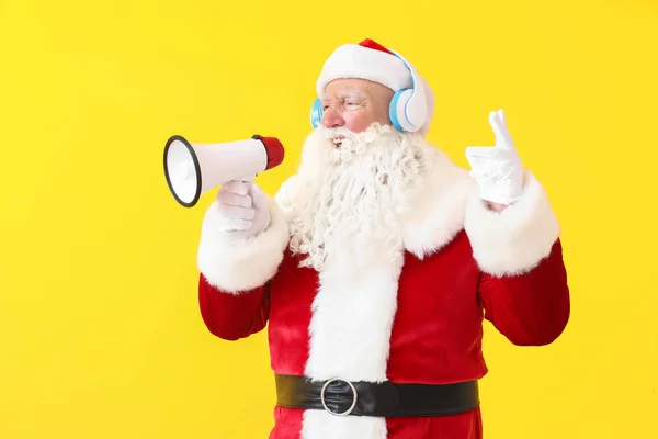 Porträt des Weihnachtsmannes mit Megafon, das Musik auf farbigem Hintergrund hört — Stockfoto