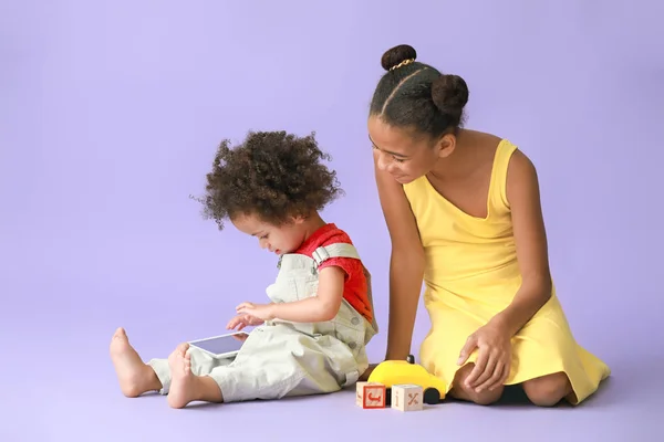 Lindas hermanas afroamericanas con tableta viendo dibujos animados en el fondo de color — Foto de Stock