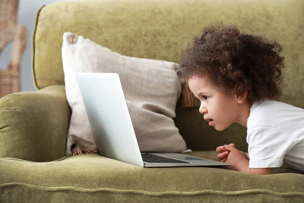 Cute African-American girl with laptop watching cartoons at home — Stock Photo, Image