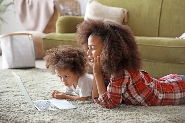 Χαριτωμένο αφρικανικά-American αδελφές με φορητό υπολογιστή βλέποντας κινούμενα σχέδια στο σπίτι — Φωτογραφία Αρχείου