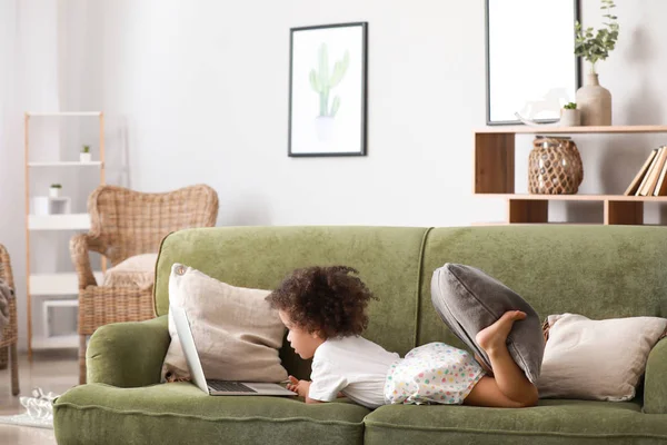 Cute African-American girl with laptop watching cartoons at home — Stock Photo, Image