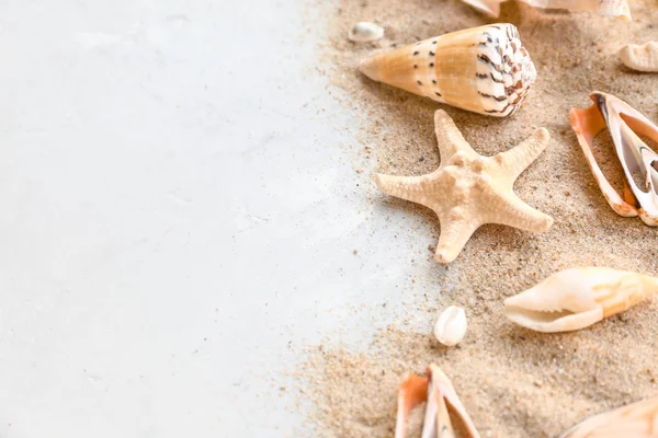 Hermosas conchas de mar, estrellas de mar y arena sobre fondo claro — Foto de Stock