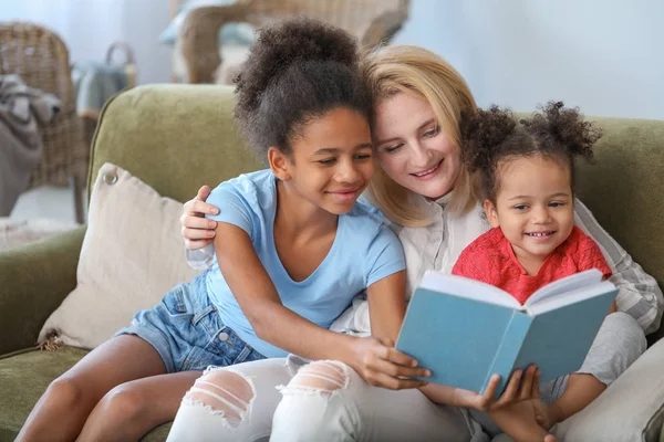 Щаслива жінка з її афро-американських дочок читаючи книгу в домашніх умовах — стокове фото