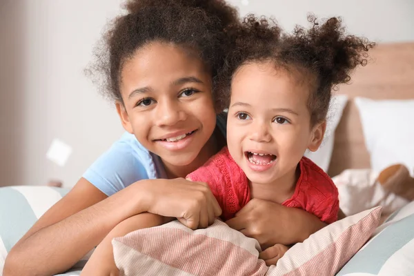 Little African-American sisters lying on bed at home — Stock Photo, Image
