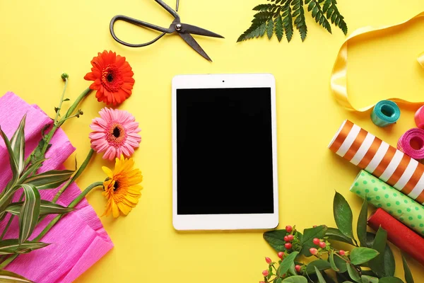 Moderner Tablet-Computer mit Blumenvorräten auf farbigem Hintergrund — Stockfoto