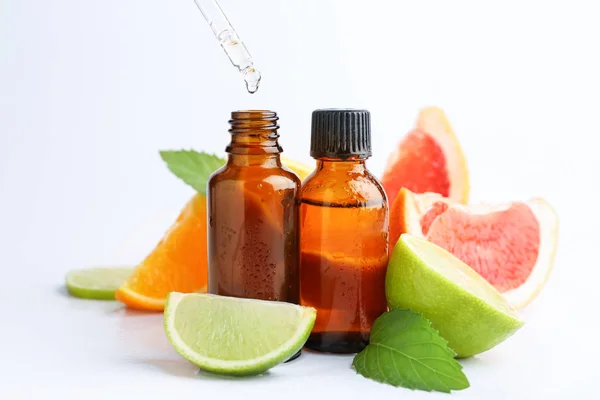 Citrus essential oil dripping from pipette into bottle on white background — Stock Photo, Image