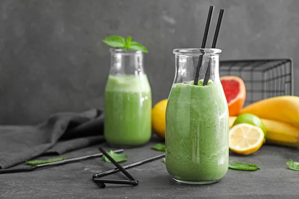 Bottles of healthy smoothie on grey table — Stock Photo, Image