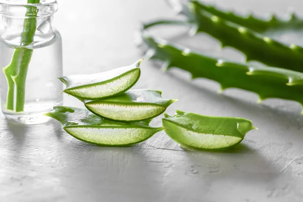 Slices of fresh aloe with essential oil on light background — Stock Photo, Image