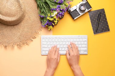 Pc klavye, şapka, fotoğraf kamerası, dizüstü bilgisayar ve renkli arka plan üzerinde çiçekler ile Kadın eller