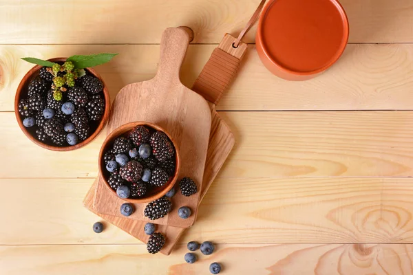 Schalen mit leckeren Brombeeren und Blaubeeren auf Holztisch — Stockfoto