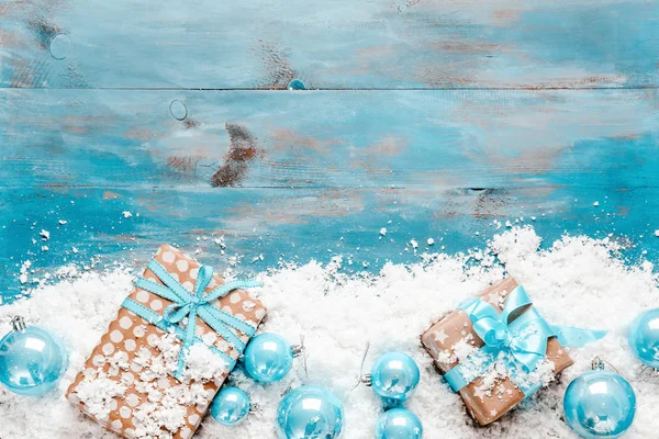 Рождественские подарочные коробки, снег и декор на цветном деревянном фоне — стоковое фото