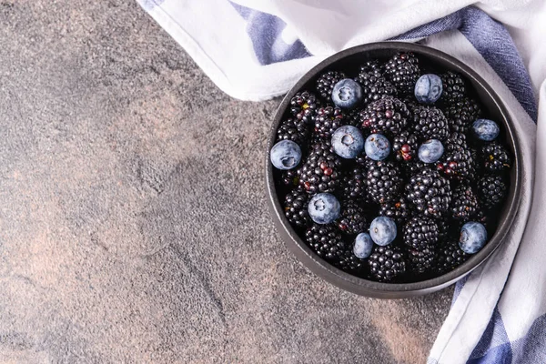 Bowl with tasty blackberries and blueberries on grey table — Stock Photo, Image