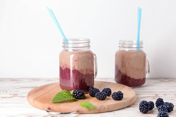 Einmachgläser mit leckerem Brombeercocktail auf weißem Tisch — Stockfoto