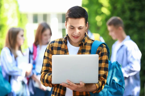 Jonge student met laptop outdoors — Stockfoto