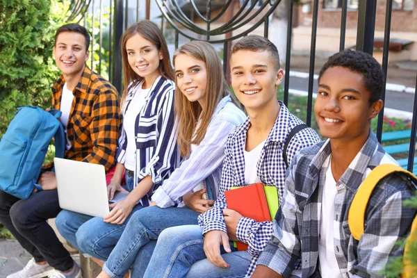 Jóvenes estudiantes sentados en el banco al aire libre —  Fotos de Stock