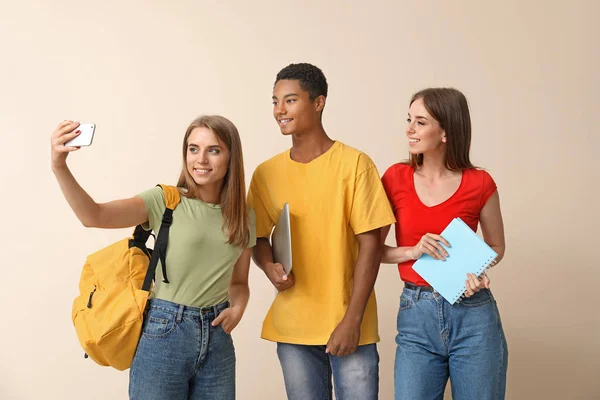 Portrait of young students taking selfie on light background — Stock Photo, Image