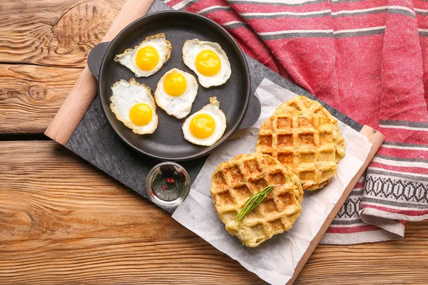 Кастрюля с жареными перепелиными яйцами и вкусными вафлями для сквоша на столе — стоковое фото