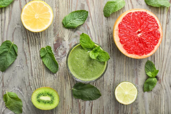 Glass of healthy smoothie and fruits on wooden table — Stock Photo, Image