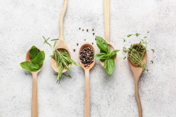 Lepels met verschillende verse kruiden en specerijen op lichte achtergrond — Stockfoto