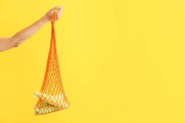 Kadın el renkli arka plan üzerinde mısır koçanları ile örgü eko çanta tutarak