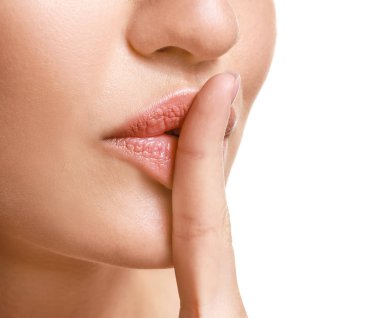 Beyaz arka planda sessizlik jesti gösteren güzel genç kadın, closeup