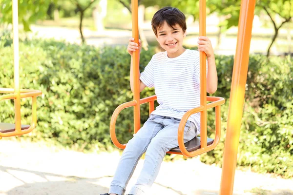 Cute little boy on swings in park — Stock Photo, Image