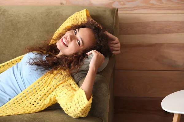 Vakker afroamerikansk kvinne som slapper av på sofaen hjemme – stockfoto