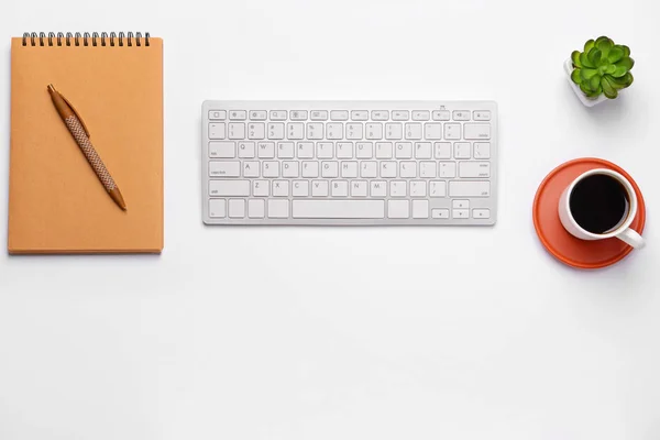 Moderne Computertastatur mit Schreibwaren und Tasse Kaffee auf weißem Hintergrund — Stockfoto