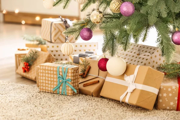 Beautiful gift boxes under fir tree in room — Stock Photo, Image