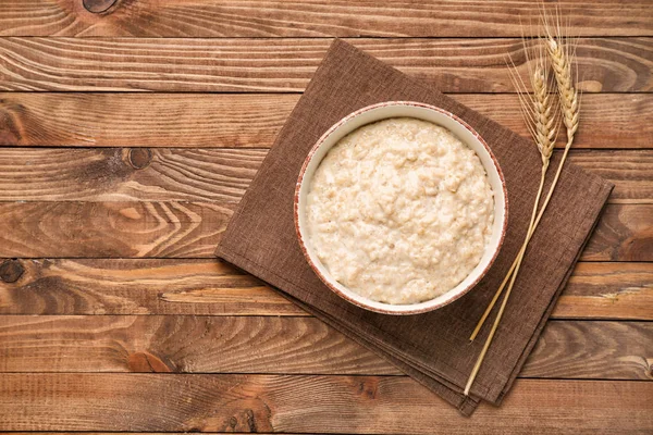 Bowl with tasty oatmeal on wooden table — Stock Photo, Image