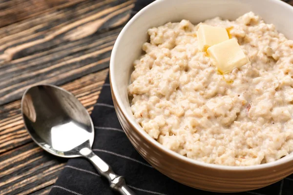 Bowl with tasty oatmeal on wooden table, closeup — Stock Photo, Image