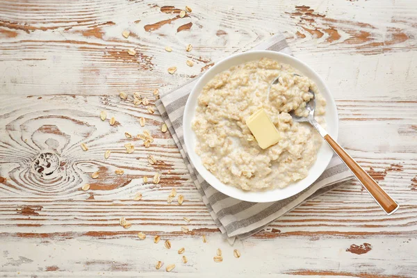 Schüssel mit leckerem Haferbrei auf weißem Holztisch — Stockfoto