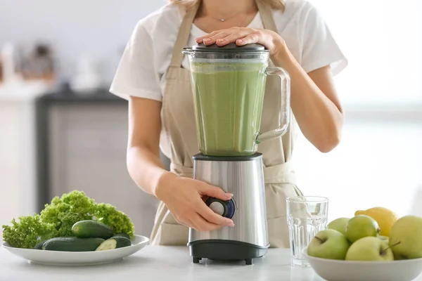 Vrouw bereidt smakelijke groene smoothie in keuken — Stockfoto