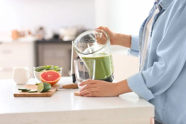 Woman pouring tasty smoothie from blender into glass in kitchen — Stock Photo, Image