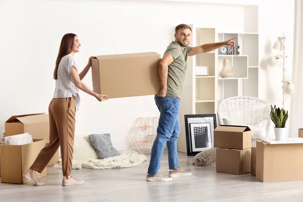 Young couple carrying boxes after moving into new house — Stock Photo, Image