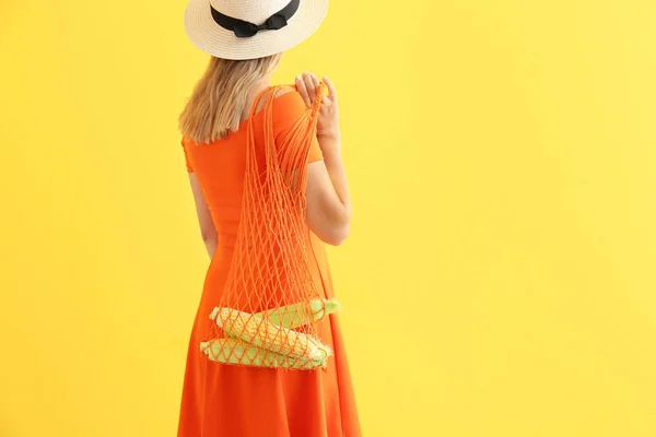 Donna che tiene mesh eco bag con pannocchie di mais su sfondo colore — Foto Stock