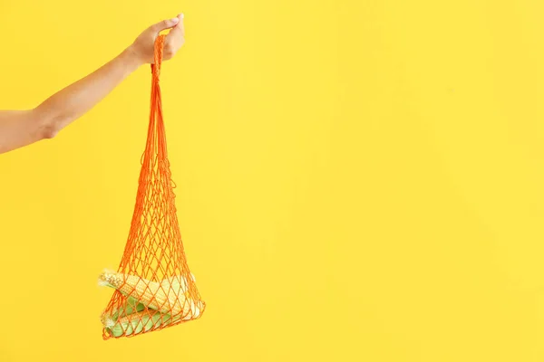 Bolso ecológico de malla de mano femenina con mazorcas de maíz sobre fondo de color —  Fotos de Stock