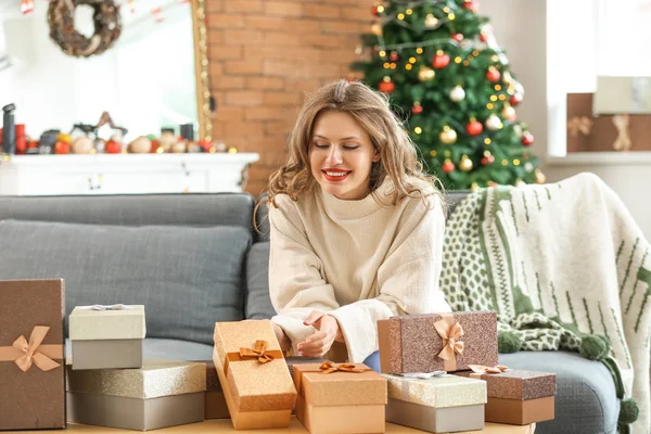 Happy young woman with Christmas gifts at home — Stock Photo, Image