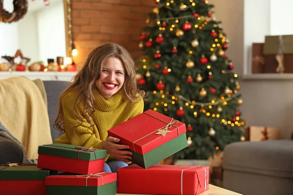 Happy young woman with Christmas gifts at home — Stock Photo, Image