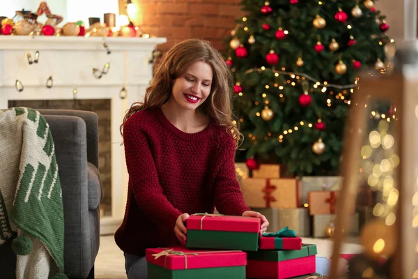 Happy young woman with Christmas gifts at home — Stock Photo, Image