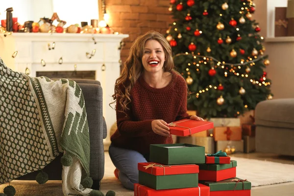 Feliz joven mujer abriendo regalos de Navidad en casa —  Fotos de Stock