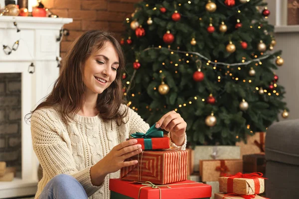 Glückliche junge Frau öffnet Weihnachtsgeschenke zu Hause — Stockfoto