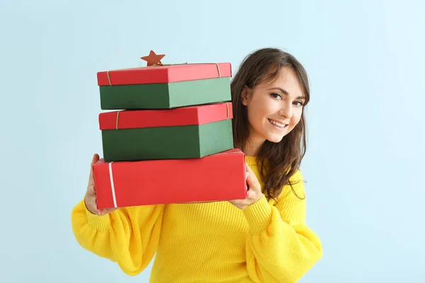 Happy young woman with Christmas gifts on light background — Stock Photo, Image