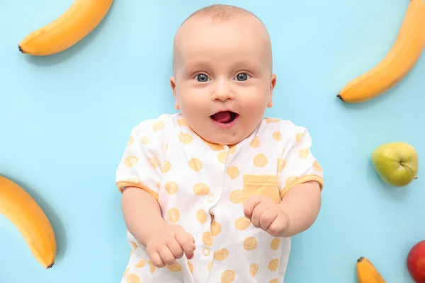 Adorable little baby with fruits on color background — Stock Photo, Image