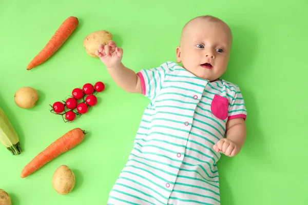 Adorable little baby with vegetables on color background — Stock Photo, Image