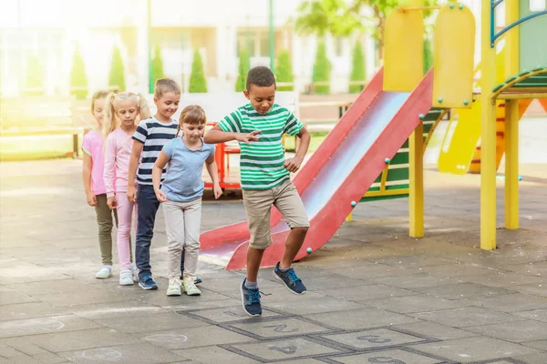 Śliczne małe dzieci bawią hopscotch w parku — Zdjęcie stockowe