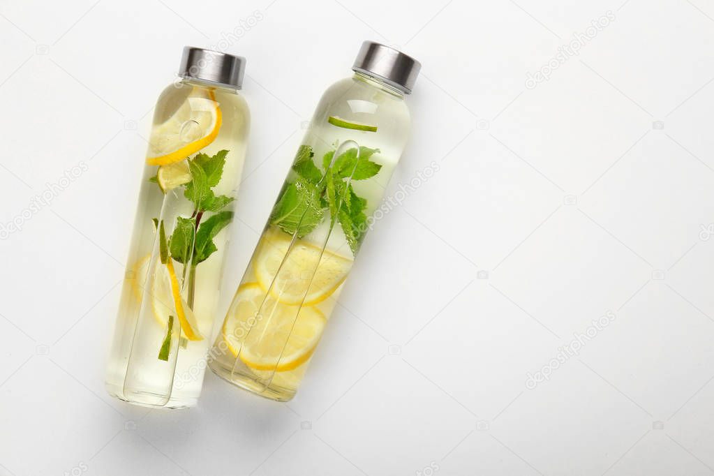 Bottles of fresh infused water on white background