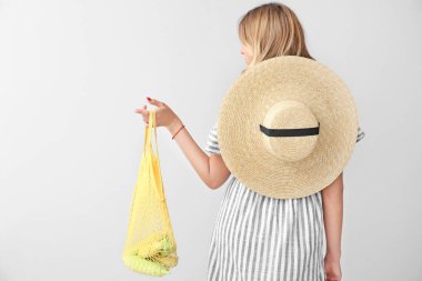 Kadın hafif arka plan üzerinde mısır ile örgü eko çanta tutan